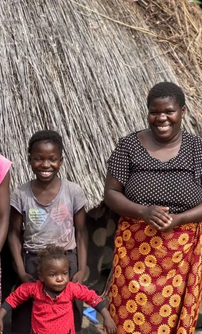 Image of Peggy and her two children, as they pose for the camera in front of their home.
